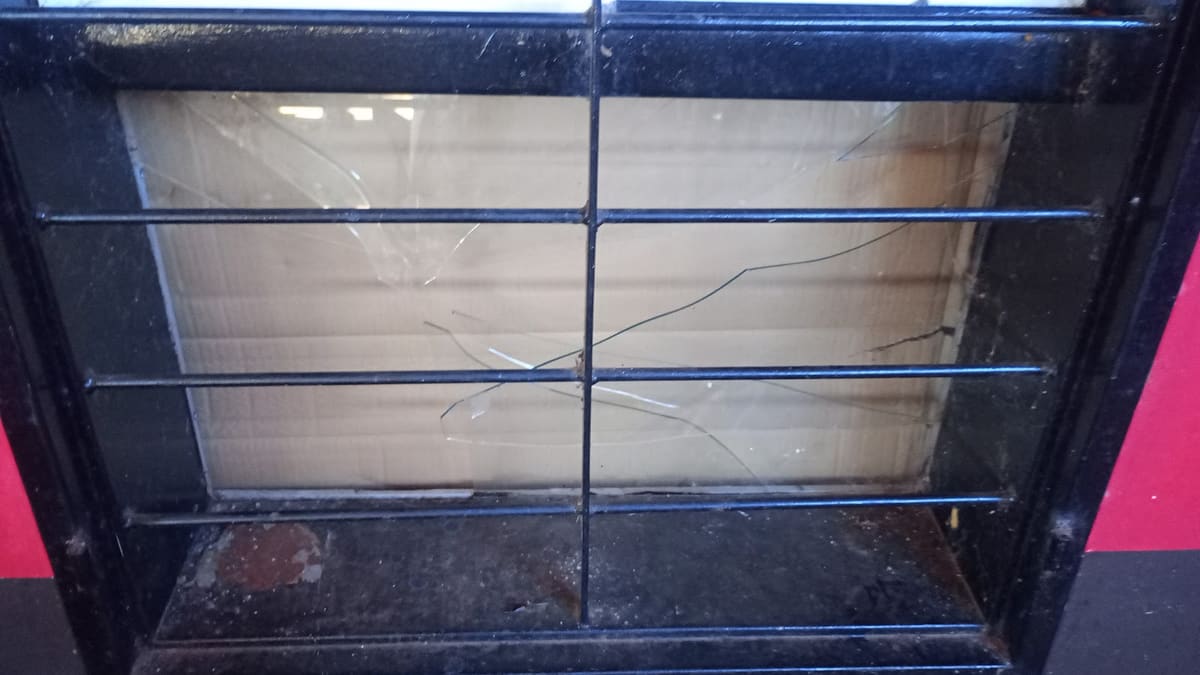 Vidrio de una ventana rajado detrás de una reja